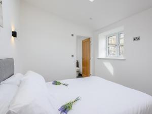 a white bedroom with a white bed with a window at Marshall Cottage in Santon