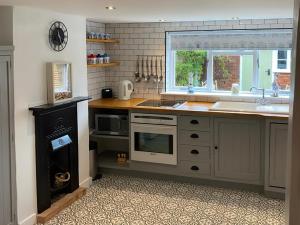 a kitchen with a sink and a stove top oven at Honey Cottage in Friston