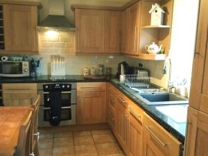 a kitchen with wooden cabinets and a stove top oven at Tyn Y Mur in Morfa Nefyn