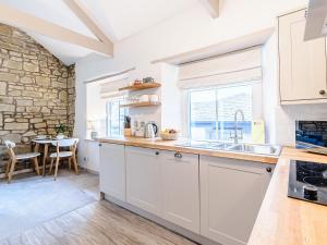 a kitchen with white cabinets and a sink and a table at Shawdon Hill Coach House in Whitby