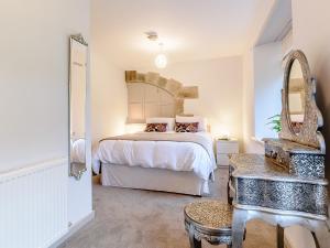 a white bedroom with a bed and a mirror at Shawdon Hill Coach House in Whitby