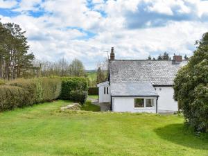 een wit huisje met een grasveld ervoor bij Manor Park Cottage in Knitsley