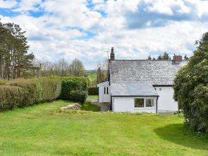 a white cottage with a grass yard in front of it at Manor Park Cottage in Knitsley