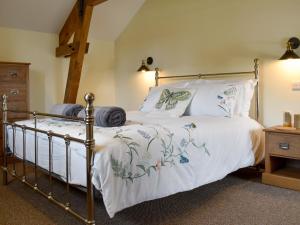 um quarto com uma cama de metal com lençóis e almofadas brancos em Bucknole Farm - The Old Shippon em Northleigh