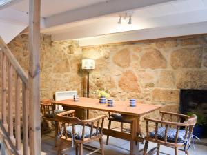 a wooden table and chairs with a stone wall at Little Trevarrack in Carbis Bay