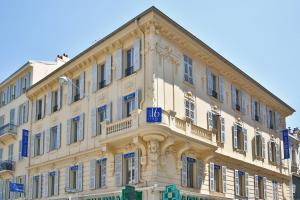 un gran edificio blanco con signos azules en Hôtel Le Seize, Nice Centre, en Niza
