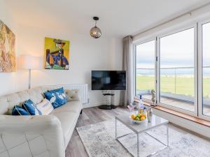 a living room with a white couch and a large window at Coastal Retreat in Amble
