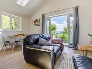 a living room with a leather couch and a table at Barn Owls Rest in Clyro