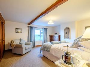a bedroom with a large bed and a chair at Curlew Cottage in Mawbray