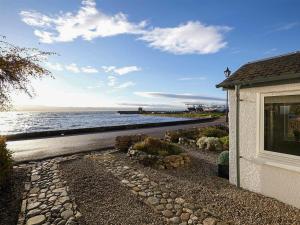 a house with a stone walkway next to the water at The Shore in Fortrose