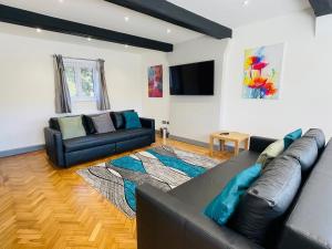 a living room with a leather couch and a flat screen tv at Warren Lodge in Little Baddow
