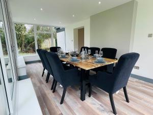 a dining room with a table and black chairs at Warren Lodge in Little Baddow