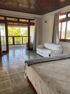 Casa Resort في Cacha Pregos: غرفة نوم بسرير واريكة ونوافذ