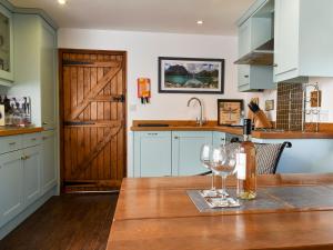 a kitchen with a wooden table with wine glasses on it at The Boathouse Uk33900 in Waldringfield