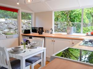 a kitchen with a table and chairs and windows at Craigrannoch Cottage in Rockcliffe