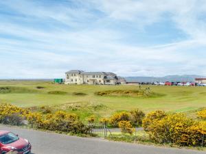 a house on a golf course with a car parked in front at Helena in Prestwick