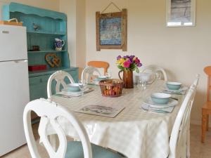 a dining room table with white chairs and a table with flowers at Cheviot View in Beal
