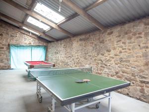 a ping pong table in a room with a stone wall at Orchard Barn in South Tawton