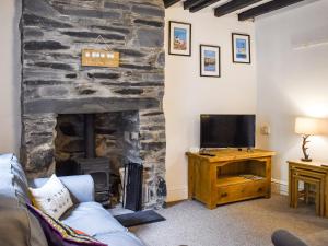 een woonkamer met een stenen open haard en een televisie bij Caer Elen in Dolwyddelan
