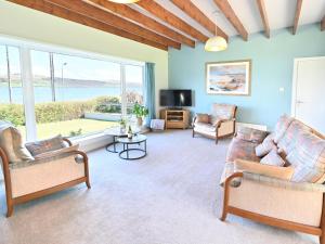 a living room with couches and a tv and a large window at Taigh An Uillt in Tighnabruaich