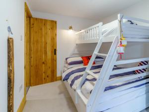 a white bunk bed with a ladder in a bedroom at Tyr Llyr in Penclawdd