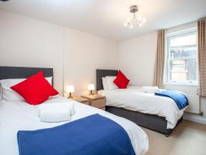 two beds in a bedroom with red and blue pillows at Waves - Great Cliff in Dawlish