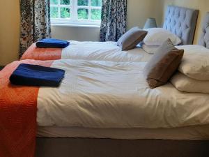 a large white bed with pillows on top of it at Duck Cottage in Winterbourne Dauntsey