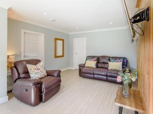 a living room with two leather couches and a table at Harebell Cottage in Addlethorpe