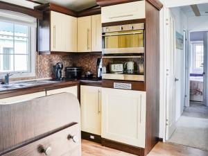 a kitchen with white cabinets and a sink at Sunnyside Lodge in Monreith