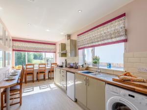 a kitchen with a sink and a dining room with a table at Harebell Cottage in Addlethorpe