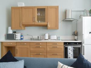 a kitchen with wooden cabinets and a stove top oven at Sandgate Apartment in Sandgate