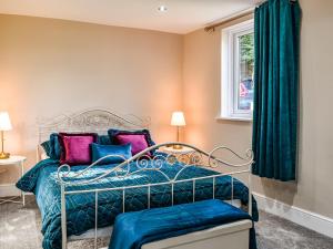 a bedroom with a bed with blue and pink pillows at Brookdale in Malpas