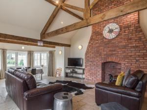 a living room with leather furniture and a brick fireplace at The Byre in Whitby