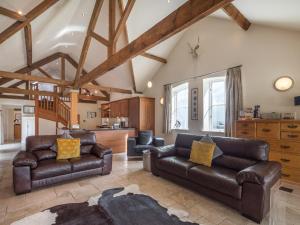 a living room with leather couches and a kitchen at The Byre in Whitby