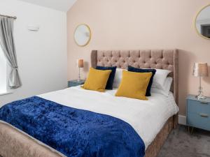 a bedroom with a large bed with blue and yellow pillows at Highgate in Kirklinton