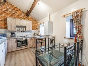 a kitchen with wooden cabinets and a brick wall at The Hay Loft in Poulton le Fylde