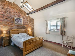 a bedroom with a wooden bed and a brick wall at The Hay Loft in Poulton le Fylde