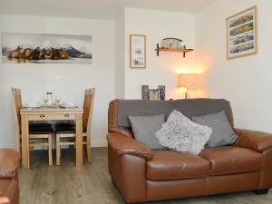 a living room with a brown leather couch and a table at Wise Cottage in Keswick