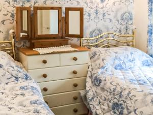 a bedroom with a bed and a dresser with a mirror at Hollyhocks Bungalow - Uk39617 in Welcombe