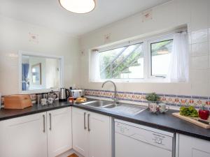 a kitchen with white cabinets and a sink and a window at Devon Court 2 in Salcombe