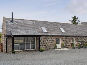 uma casa de pedra com janelas e um telhado em Longcroft Dairy em Oyne