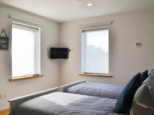 1 Schlafzimmer mit 2 Betten, einem TV und 2 Fenstern in der Unterkunft Healair in Garrabost