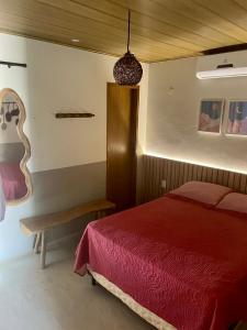 Schlafzimmer mit einem roten Bett und einer Bank in der Unterkunft CHALEVILLE Coqueiro 46 in Luis Correia