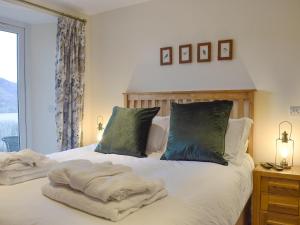 um quarto com uma cama com lençóis brancos e almofadas verdes em Chapelburn em Lawers