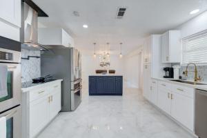 a large kitchen with white cabinets and a blue island at Elegante casa cerca de Galleria Mall, NRG, Centro Medico! in Houston