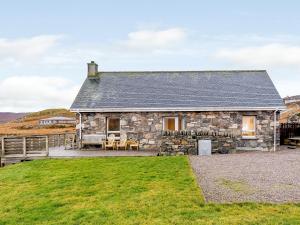 una casa de campo de piedra con un patio de césped delante de ella en Riof Ocean Cottage - Uk7125, en Valtos