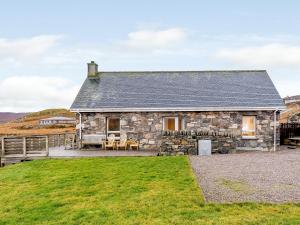 a stone cottage with a grassy yard in front of it at Riof Ocean Cottage - Uk7125 in Valtos