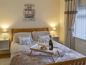 a bed with a table with a bottle of wine on it at Hafod Y Bryn in Benllech
