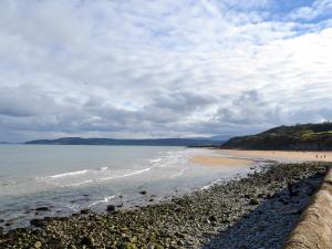 a beach with a fence and the ocean on a cloudy day at Hafod Y Bryn in Benllech