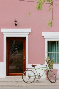 una bicicleta verde estacionada frente a un edificio rosa en Hostal Tunich Naj & Hotel, en Valladolid